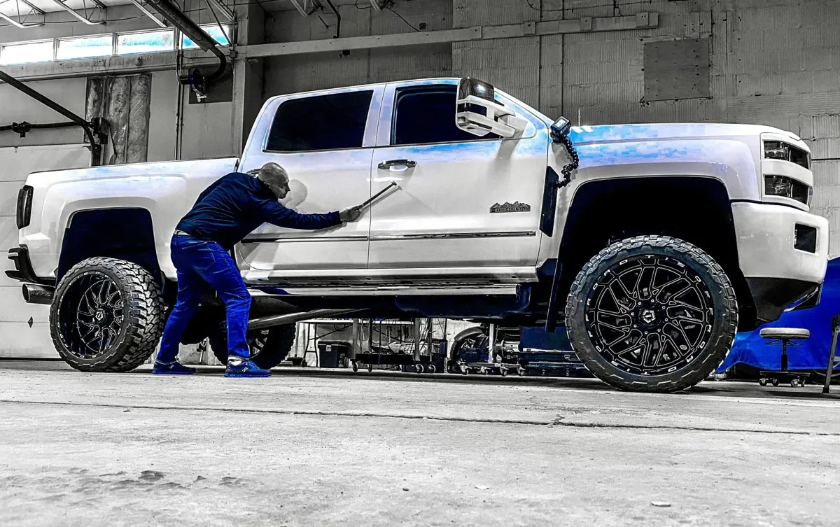 Precision Dent technician performing paintless dent repair on a white pickup truck