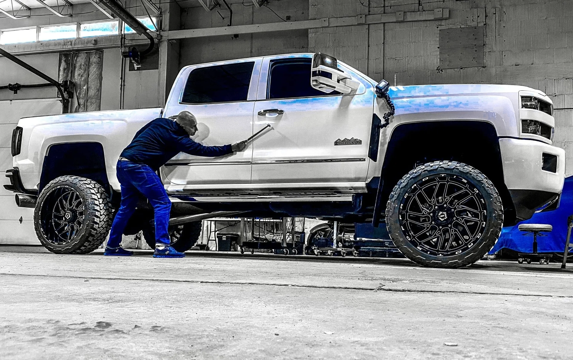 Precision Dent technician performing paintless dent repair on a white pickup truck