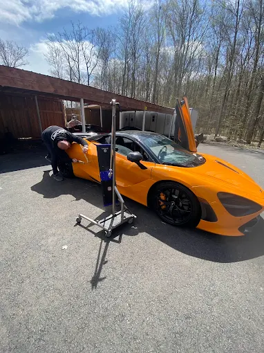 Supercar panel being repaired with paintless dent repair to protect factory paint
